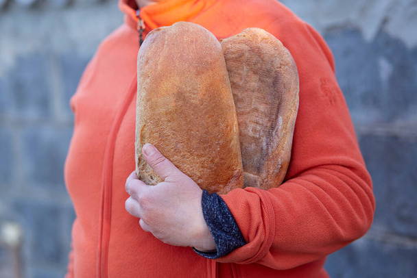 Женщина держит в руках две буханки белого хлеба - Фото, изображение