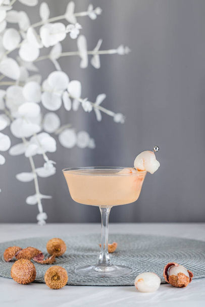 Κοκτέιλ Ρόζ Λίτσι. Ποτήρι σαμπάνιας coupe γεμάτο με ροζ lychee cocktail ή mocktails που περιβάλλεται από συστατικά και εργαλεία bar. - Φωτογραφία, εικόνα