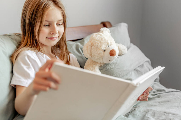 Child girl with teddy bear toy in the bed - Fotoğraf, Görsel