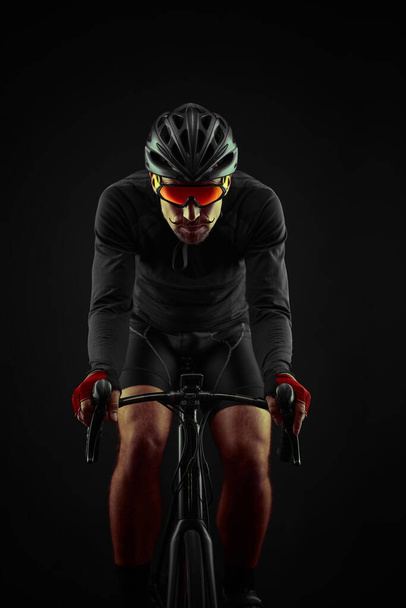 male cyclist riding road bicycle on black background - Foto, afbeelding