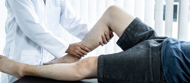 Fisioterapeuta haciendo tratamiento curativo y rehabilitación piernas lesionadas y tobillo de paciente mediante estiramiento y ejercicio físico con terapia en clínica de salud - Foto, Imagen