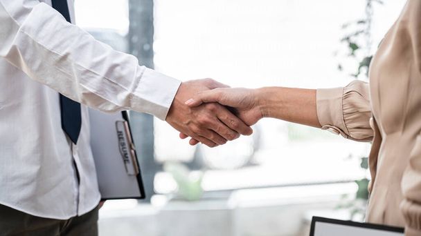 Woman employer is shaking hands to congratulate with the new employee after successful with job interview and signing contract in meeting room at office - Photo, image