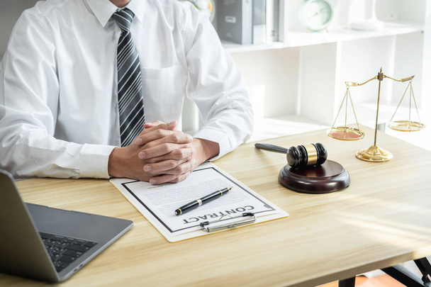 Male lawyer or jurist working with litigation contract paper documents of the estate lawsuit, Law books and wooden gavel on table in office. - Photo, image