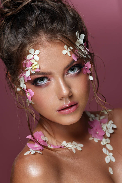 Beautiful caucasian woman with flowers on pink background. - Фото, зображення