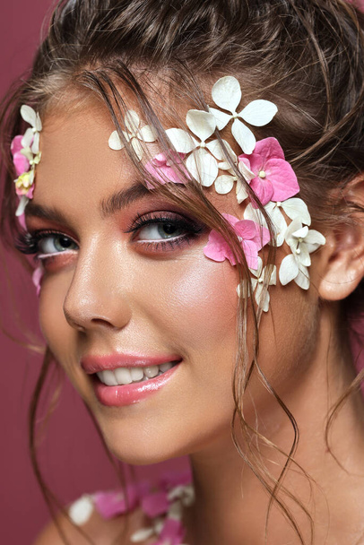 Beautiful caucasian woman with flowers on pink background. - 写真・画像