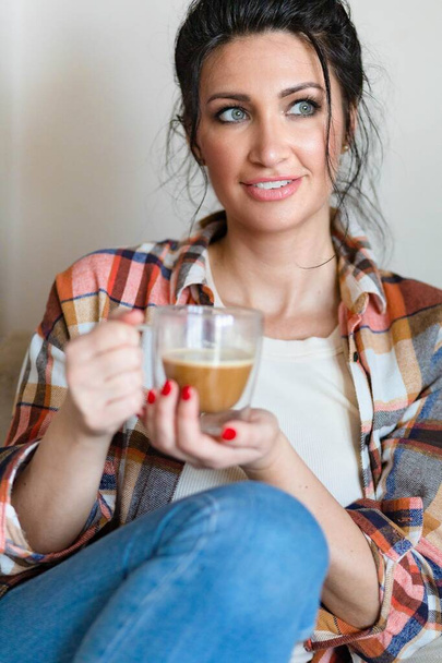 Blue eyed middle aged woman sitting with a cup of coffee - Фото, зображення