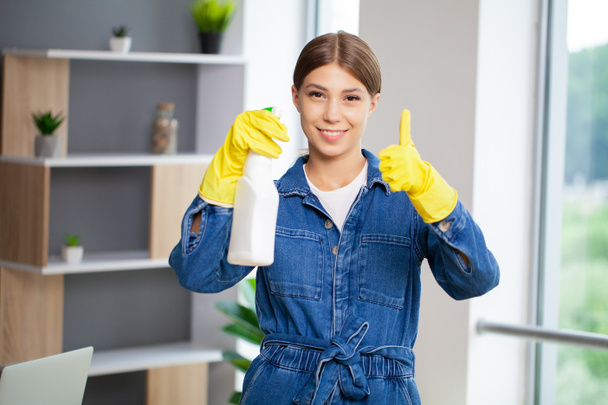 Retrato de uma jovem empregada feliz que está limpando o escritório - Foto, Imagem