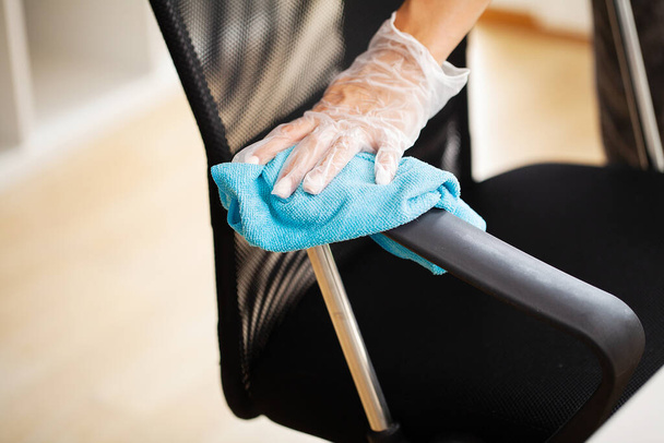 Mujer limpia muebles en la oficina con una toallita desinfectante húmeda - Foto, Imagen
