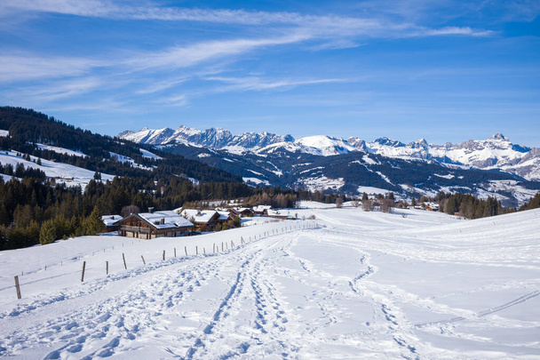 Tato fotografie krajiny byla pořízena v Evropě, ve Francii, Rhone Alpes, v Savojsku, v Alpách, v zimě. Vidíme turistické stezky, kterým dominuje Chaine des Aravis, pod sluncem. - Fotografie, Obrázek