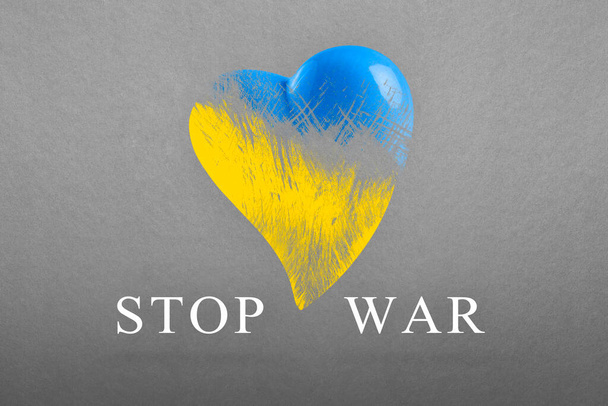 Stop war in Ukraine. Save Ukraine. The heart is painted in the colors of the Ukrainian flag - blue and yellow. No war text, poster on gray background - Zdjęcie, obraz