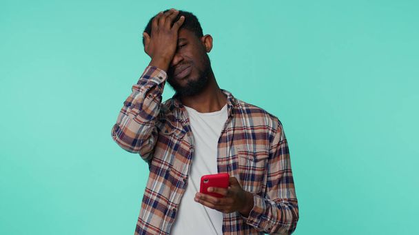 hombre afroamericano utilizar la navegación del teléfono móvil, pierde, resultados repentinos de la lotería, mala fortuna, pérdida - Foto, Imagen