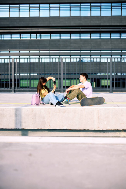 Teenage couple sitting on railroad station and taking photos. - Foto, Imagen