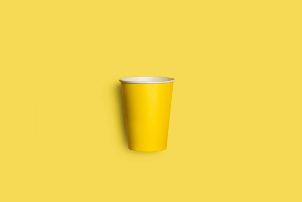 Żółty jednorazowy kubek na żółtym tle z przestrzenią do kopiowania - Zdjęcie, obraz