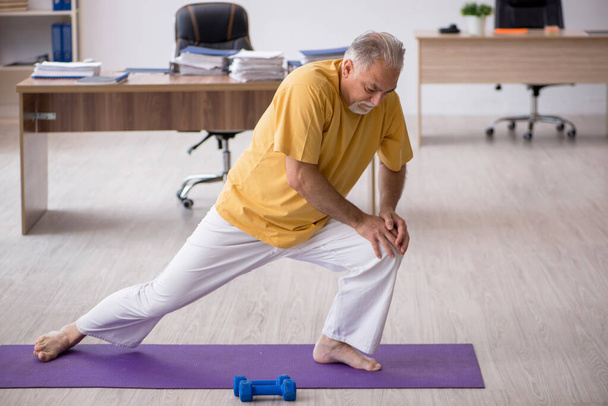 Old businessman employee doing sport exercises in the office - Photo, image
