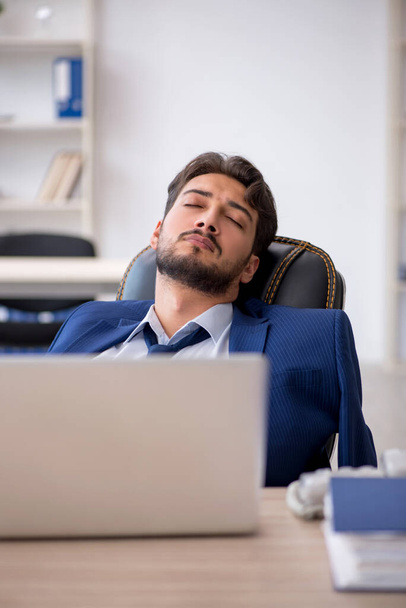 若い男性従業員はオフィスで非常に疲れている - 写真・画像