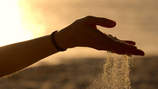 Young woman playing with sand on a beach at sunset - slow motion - Foto, Imagen