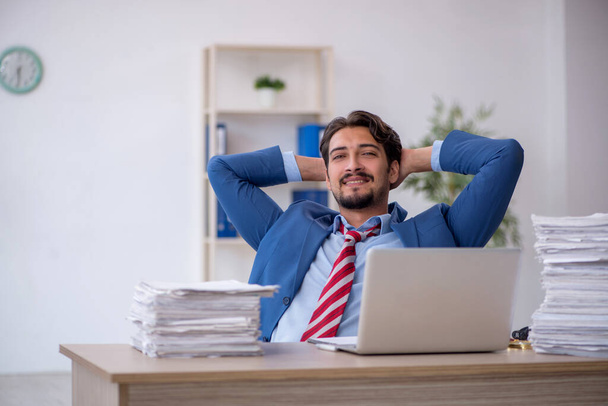 Young male employee and too much work in the office - Φωτογραφία, εικόνα
