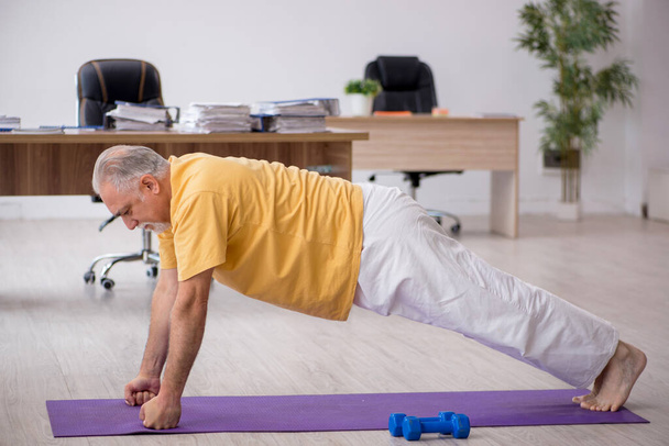 Old businessman employee doing sport exercises in the office - Photo, Image