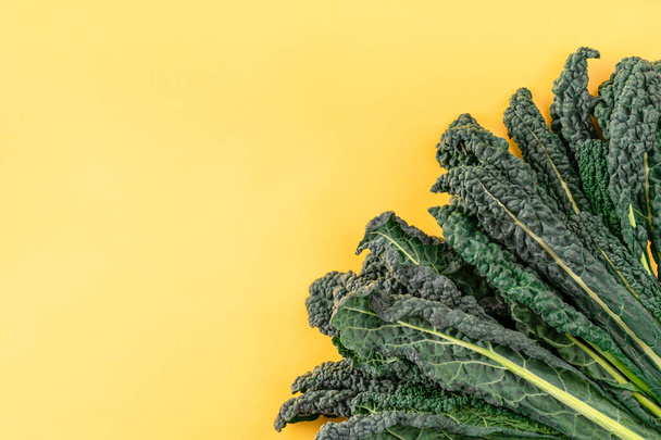 Kale pozostawia warzywa sałatkowe na żółtym tle. kapusta czarna, włoska jarmuż, jarmuż toskański. Widok z góry, z góry - Zdjęcie, obraz