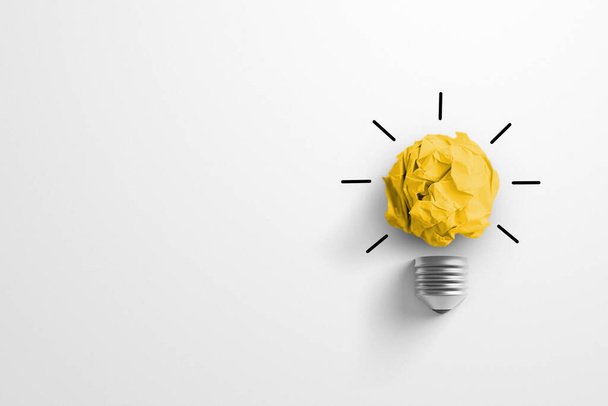 Ideas de pensamiento creativo y concepto de innovación. Pelota de chatarra de papel color amarillo con símbolo de bombilla sobre fondo blanco - Foto, Imagen