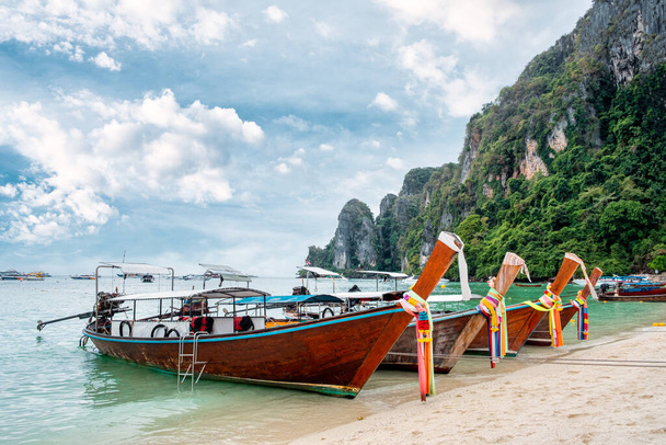 タイ、クラビのピピ島と石灰岩の山のビーチに停泊木製の長い尾船 - 写真・画像