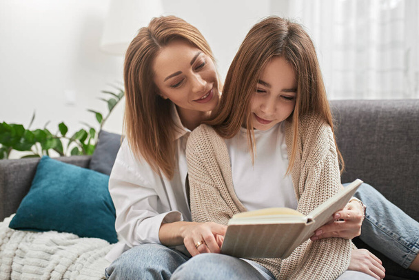 Mother and daughter reading book together - Фото, изображение