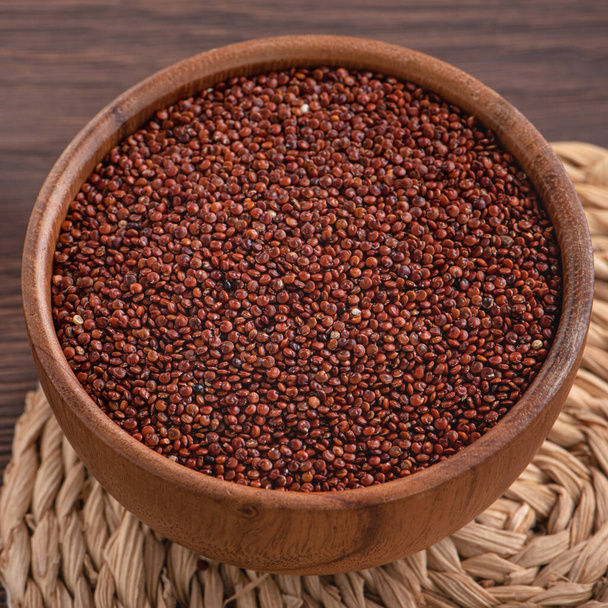 Close up of organic red quinoa in a bowl on wooden table background. - Фото, изображение