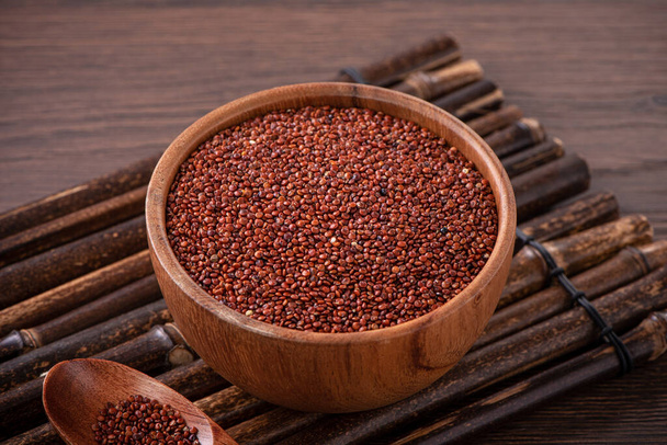 Close up of organic red quinoa in a bowl on wooden table background. - Фото, изображение
