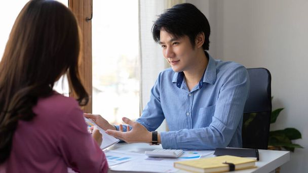 Asesor de inversión masculino asiático guapo o agente de seguros que tiene una reunión con el cliente femenino en la oficina. - Foto, imagen