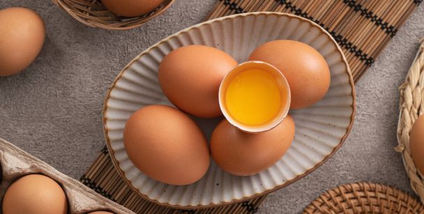 Top view of fresh brown chicken eggs in a plate on gray table background. - Фото, изображение