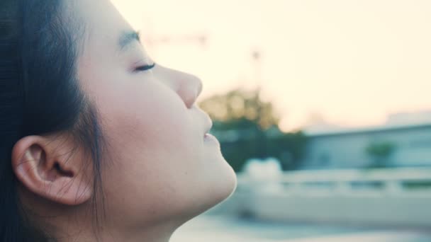 Vonzó ázsiai sportnő csukott szemmel és friss levegőt szívva a parkban. Egészség wellness életmód koncepció. - Felvétel, videó