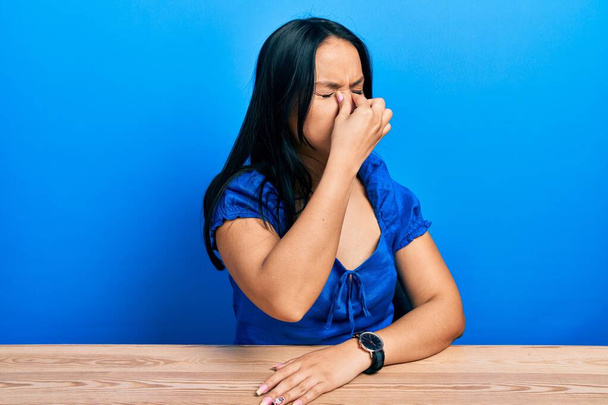 Piękna latynoska kobieta z kolczykiem w nosie siedząca na stole zmęczona pocieraniem nosa i oczu uczucie zmęczenia i bólu głowy. koncepcja stresu i frustracji.  - Zdjęcie, obraz