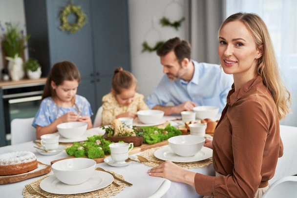 Portret van een blanke vrouw en haar familie aan tafel op de achtergrond - Foto, afbeelding