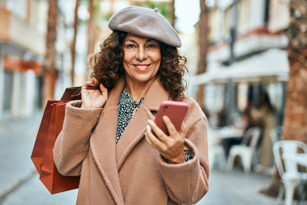 Medioevo donna ispanica utilizzando smartphone shopping in città. - Foto, immagini