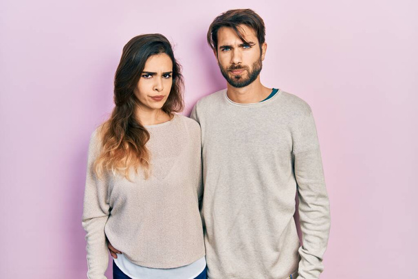 Mladý hispánský pár v neformálním oblečení skeptický a nervózní, zamračený kvůli problému. negativní osoba.  - Fotografie, Obrázek