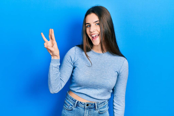Giovane adolescente bruna indossa maglione casual mostrando e indicando con le dita il numero tre mentre sorride fiducioso e felice.  - Foto, immagini