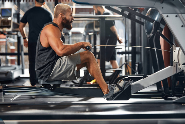 Nogi treningowe w symulatorze, sportowiec pracuje z nogami na symulatorze, ćwicząc mięśnie nóg. - Zdjęcie, obraz