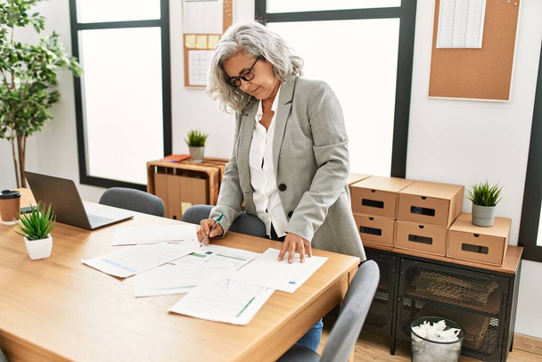 Femme d'affaires aux cheveux gris d'âge moyen travaillant au bureau. - Photo, image