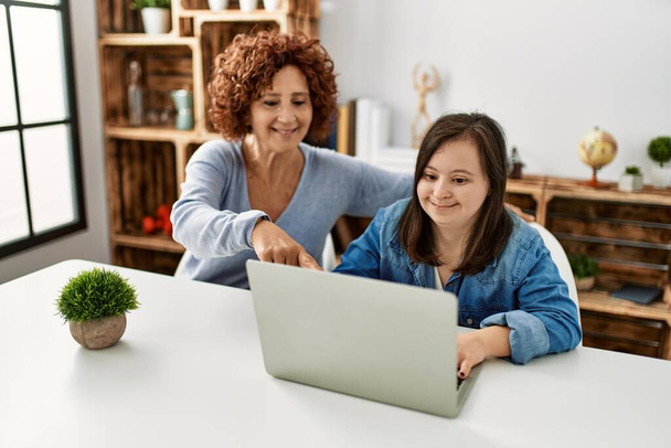 Mature mother and down syndrome daughter using computer laptop at home - Photo, Image
