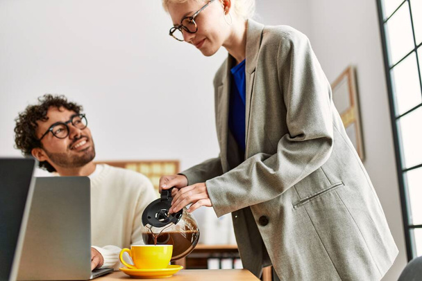 Бизнесмен наливает кофе своему партнеру в офисе - Фото, изображение