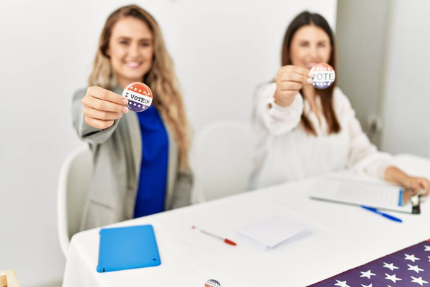 2人の若いアメリカ人女性が選挙表大学で働くバッジに投票しました. - 写真・画像