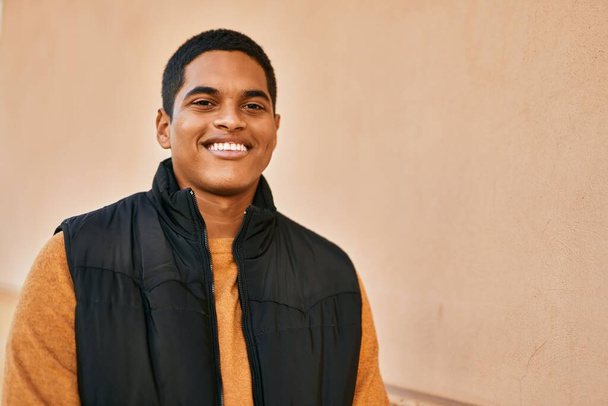 Jonge latijnse man glimlachend blij staand in de stad - Foto, afbeelding