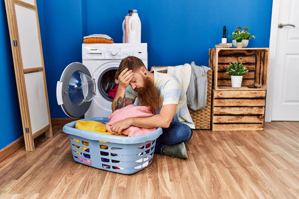 Молодий рудий чоловік підкреслив прання одягу в пральні
 - Фото, зображення