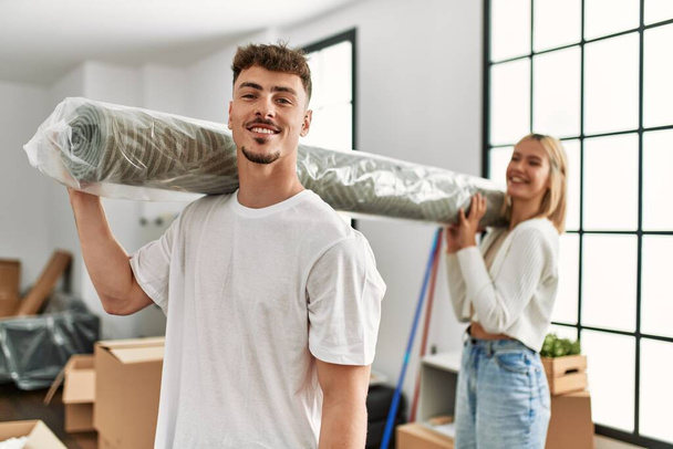 Молода біла пара посміхається щасливий килим, що стоїть в новому будинку
. - Фото, зображення
