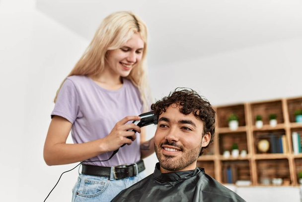 Jeune femme coupe les cheveux à son petit ami à la maison. - Photo, image