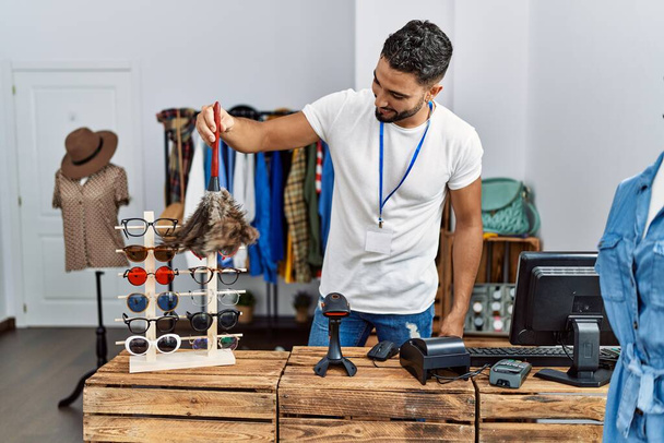 młody arabski człowiek sklepikarz sprzątanie okulary pracy w sklepie odzieżowym - Zdjęcie, obraz