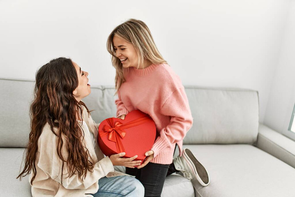 Young woman surprising her girlfriend with valentine gift at home. - Φωτογραφία, εικόνα