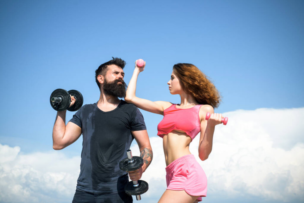 Man and woman training with dumbbells, athletic sport couple exercise outdoor. - Foto, imagen