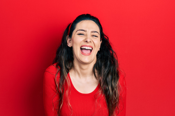 Mujer hispana joven vistiendo ropa casual sonriendo y riendo en voz alta porque divertida broma loca con las manos en el cuerpo.  - Foto, imagen
