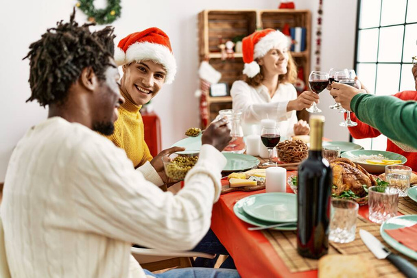 Gruppe junger Leute lächelt glücklich beim Weihnachtsessen zu Hause. - Foto, Bild